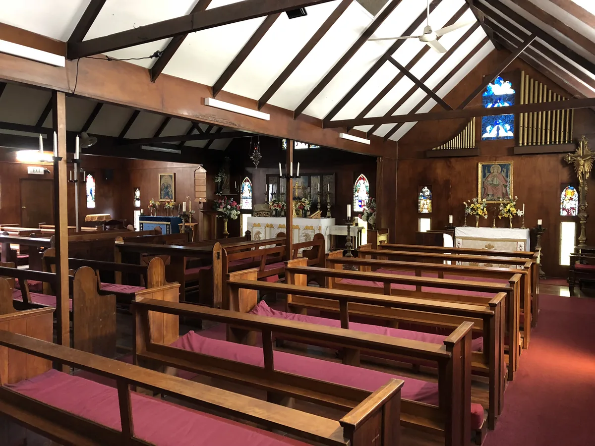 Heritage chapel interior with timber pews and stained glass.